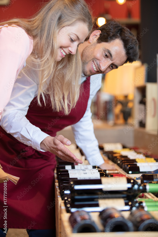 Fototapeta premium male sommelier helping woman to buy bottle of wine