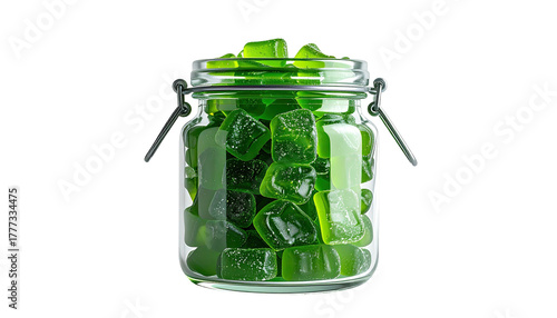 Green gummy candies piled high in a glass jar, dark background