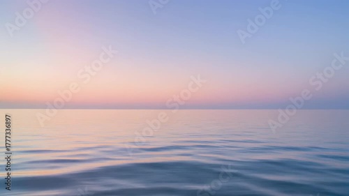 Calm pastel sunset over a serene ocean with gentle ripples on the water surface.