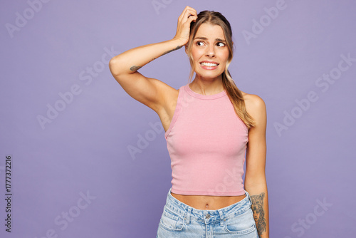 Young sad shocked mad mistaken woman she wearing pink tank top casual clothes put hand on head looking aside isolated on plain pastel light purple wall background studio portrait. Lifestyle concept.