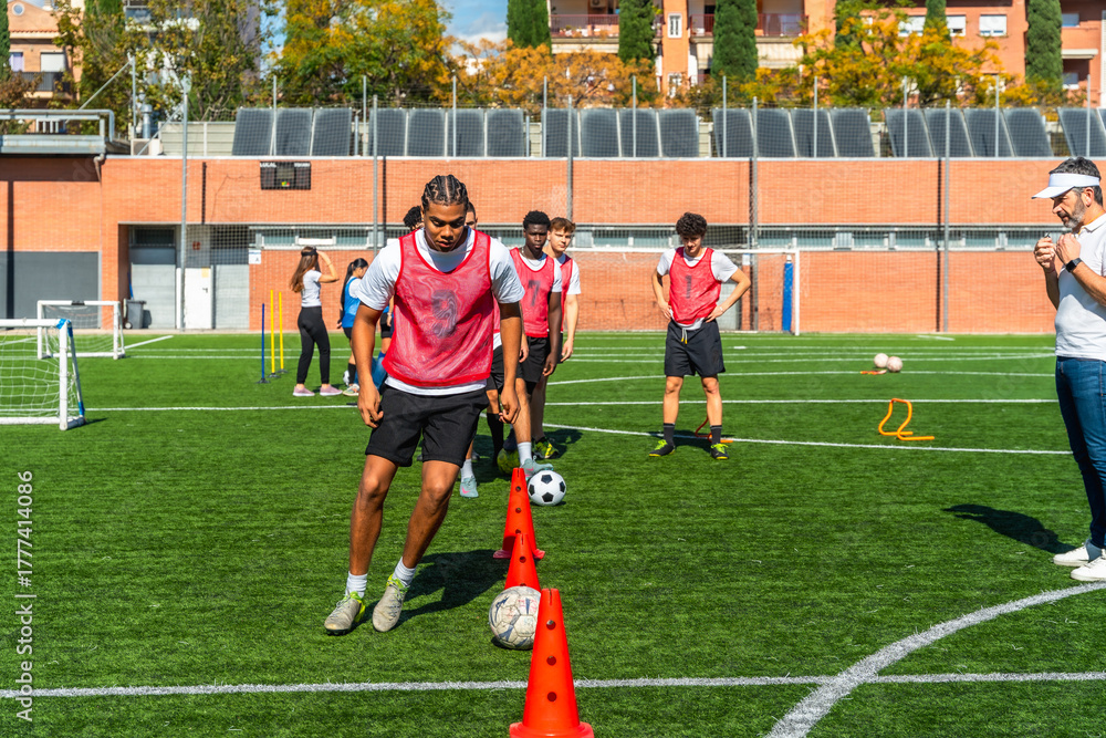 Fototapeta premium Young men training football agility drills on a field