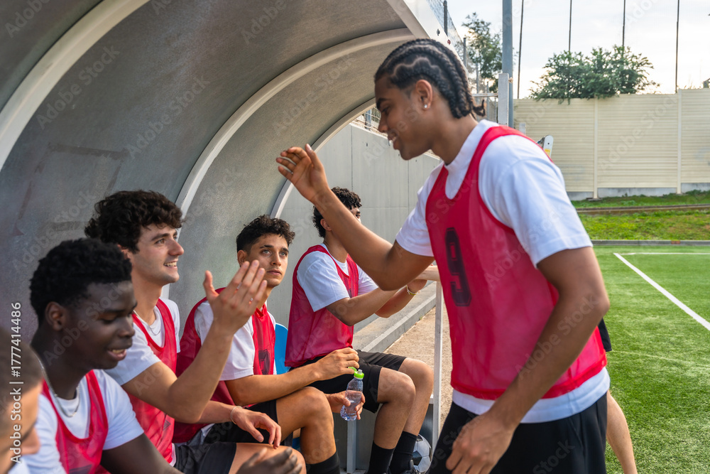 Naklejka premium Diverse soccer team high fiving in dugout, celebrating success