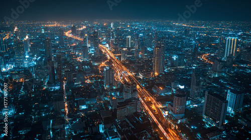 An aerial view of a vibrant cityscape illuminated at night, a symbol of urban development and progress. The intricate network of buildings and streets comes alive under the artificial lights.
