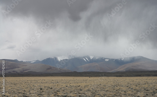Thunderclouds and rain coming from snowy North Chuisky Ridge over the steppe