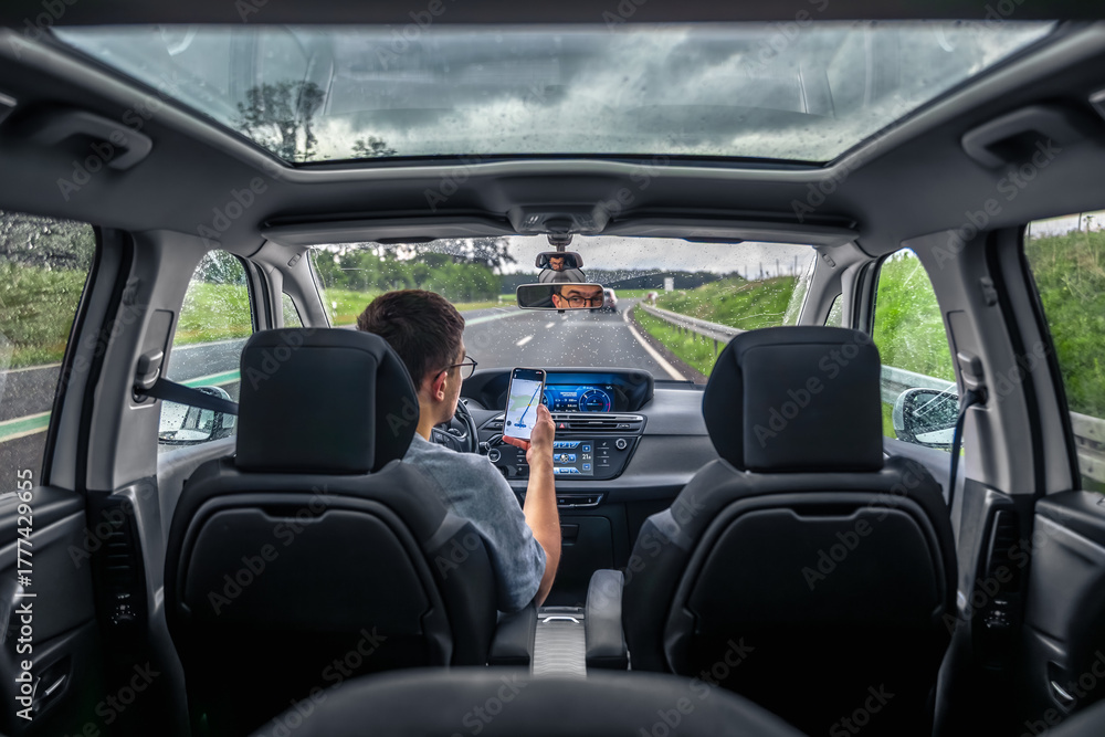 Fototapeta premium Driver using smartphone on rainy highway. Navigation on the move.