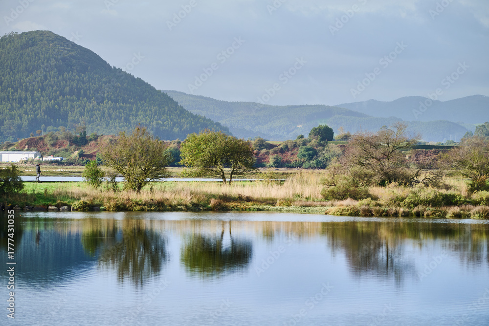 Fototapeta premium Person walking along tranquil mountain lake landscape