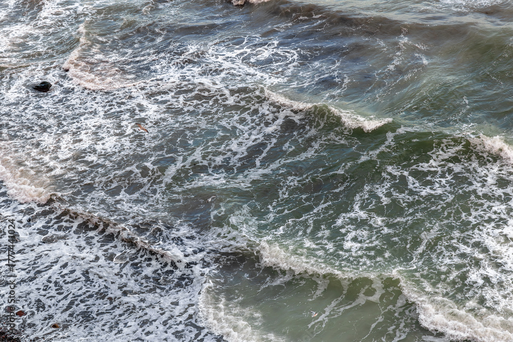 Fototapeta premium Foamy waves on greenish sea, rhythm and texture. Sea foam closeup.
