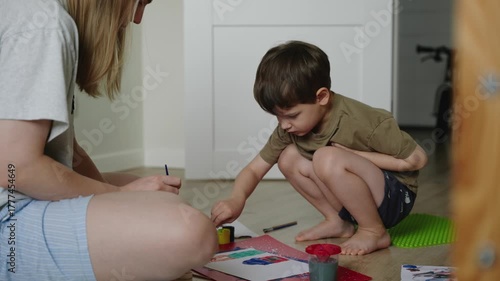 Mother and son engaged in painting on the floor, showcasing creativity and bonding