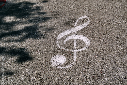 Clef de sol blanche dessinée sur le sol. Symbole musical peint sur le goudron de la rue.