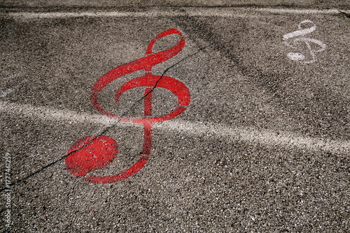 Clef de sol rouge dessinée sur le sol. Symbole musical peint sur le goudron de la rue.