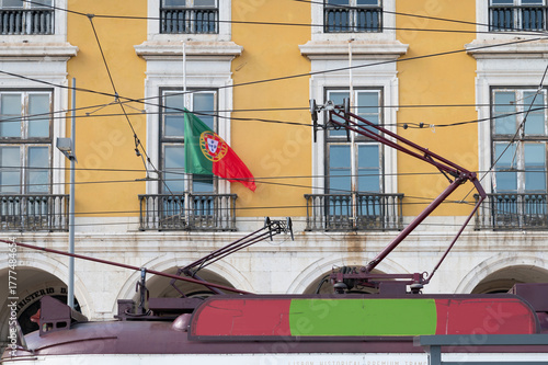 lisboa, tranvia electrico en la plaza del comercio con la bandera de portugal.