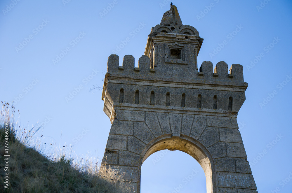 Obraz premium Low-Angle View of a Historic Stone Tower Archway and Battlements Against Clear Blue Sky