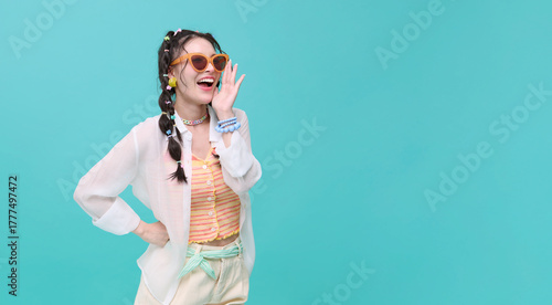Cheerful young asian teen woman shout story or making announcement representing fun communication summer lifestyle isolated on blue copy space background.