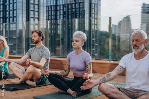 Serene people in activewear practising yoga on hotel rooftop terrace. Meditation together during outdoor class
