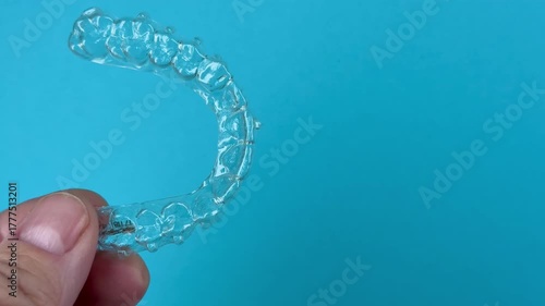 The doctor holds in his hand transparent aligners plastic braces retainers for straightening teeth on a blue background