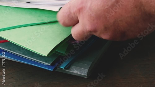 Sorting through colorful folders filled with documents on a dark wood table, looking for specific papers for project management