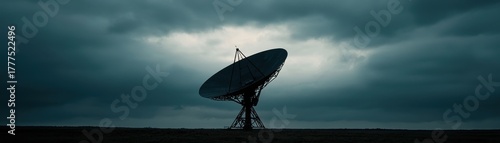 Large satellite dish antenna silhouetted against a dramatic cloudy sky