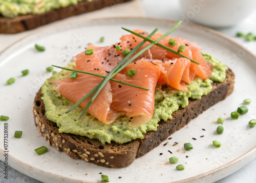 Avocado toast with smoked salmon slices and chives on whole grain bread. Healthy breakfast or brunch dish, rich in omega-3 and vitamins. Delicious snack.