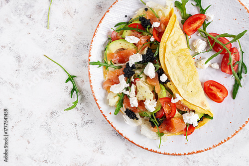 Healthy breakfast. Quesadilla with omelette, salmon, avocado, feta cheese, black caviar and tomatoes. Keto, ketogenic lunch. Top view