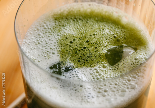 Close-up of foamy iced matcha latte in glass