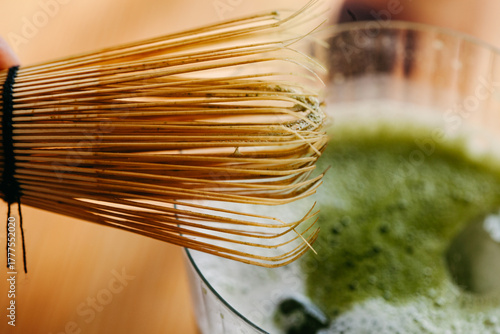 Close-up of bamboo whisk over glass of iced matcha tea