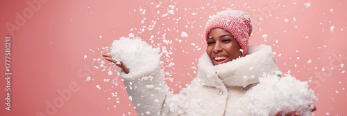 African American woman in winter coat joyfully playing with snowflakes, copy space for design