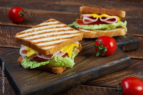 Delicious sandwich with ham, cheese, tomato and lettuce on toasted bread. Perfect lunch or snack idea