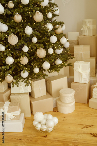 Gift boxes under a contemporary Christmas tree in a home, adorned with holiday Xmas ornaments