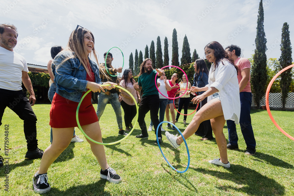 Obraz premium Diverse large group of latin american people playing with hula hoop outdoors in Mexico. Hispanic multi generation family or friends enjoying time together