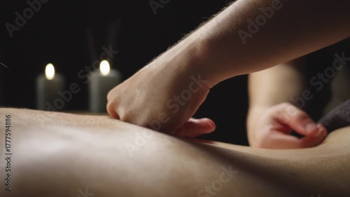 Wallpaper Mural A close-up of a massage therapist's hands gently massaging a client's back in a serene, dimly lit room with candles, creating a relaxing atmosphere. The focus is on the therapeutic touch. Torontodigital.ca
