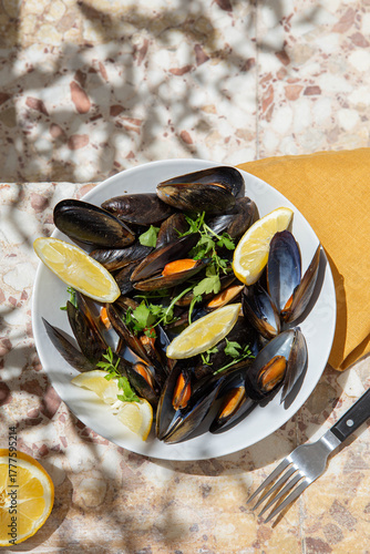 Traditional Spanish mussels dish with lemon and tree shadows in sunny rustic outdoor setting
