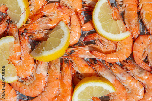 Top view of cooked shrimps with lemon under hard sunlight