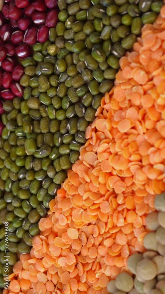 Vibrant assortment of raw dry legumes, including lentils, chickpeas, and various beans, rotating as a colorful and textured background showcasing a variety of plant based protein sources
