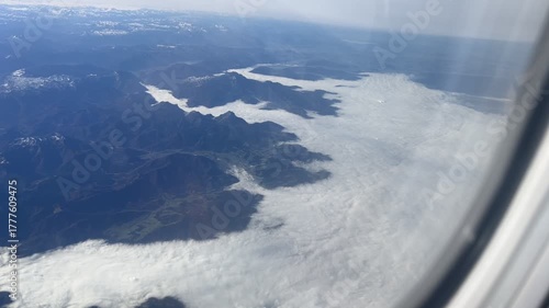 An aerial shot of a hilly green terrain with low clouds lying in the valley