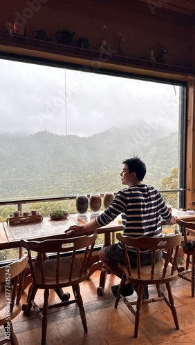 Handsome Man Relaxing in Cafe with Beautiful Morning Misty Valley View