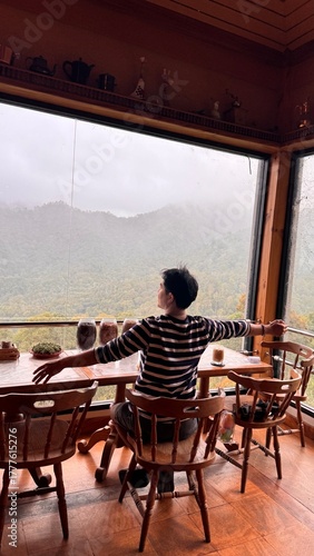 Handsome Man Relaxing in Cafe with Beautiful Morning Misty Valley View