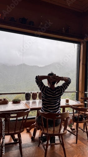 Handsome Man Relaxing in Cafe with Beautiful Morning Misty Valley View