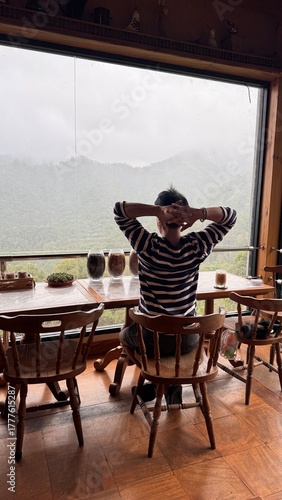 Handsome Man Relaxing in Cafe with Beautiful Morning Misty Valley View