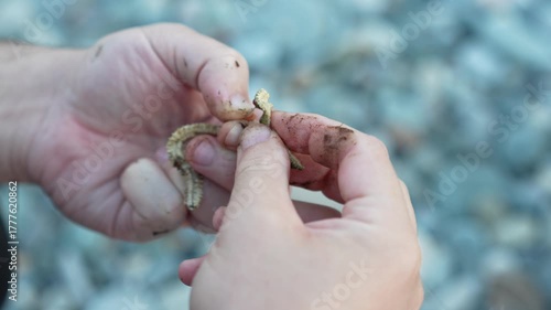 Preparing for Fishing Trip – Man Carefully Places Worm on Hook by Water