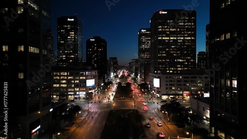 Aerial view of a busy city street at night with car lights and illuminated buildings