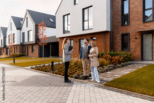 Real estate agent showing new modern townhouses to young couple