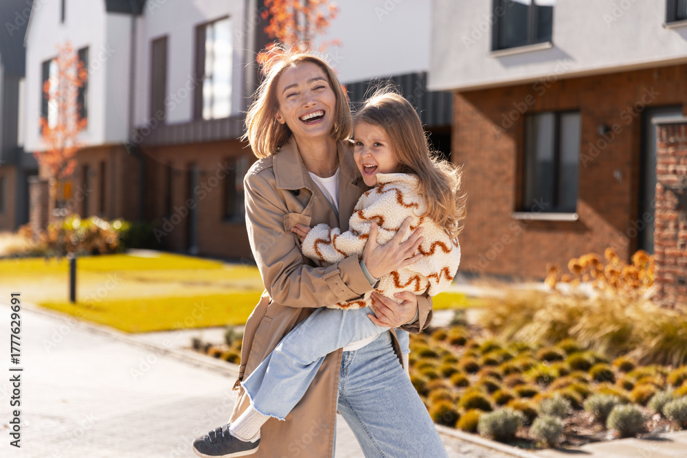 Naklejka premium Mother and daughter laughing, hugging outdoors on sunny autumn day