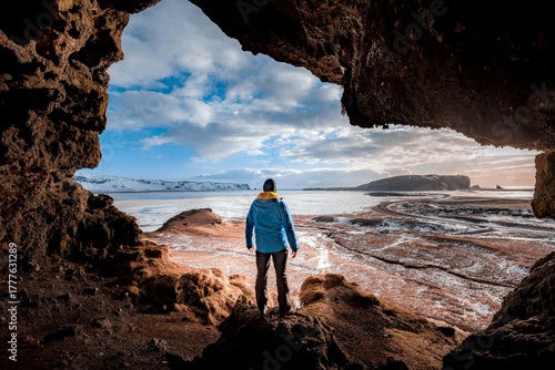 Back view of a person standing inside the Loftsalahellir cave, Geitafell mountain, South Coast Iceland, Dyrholaey Peninsula and black sand beach, Beautiful nature landscape background for wallpaper