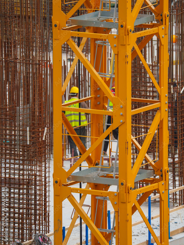 Fototapeta premium Construction Workers Among Reinforcement Bars and Heavy Equipment