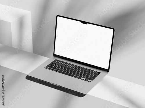 Laptop with a bright white screen and plant shadow on desk