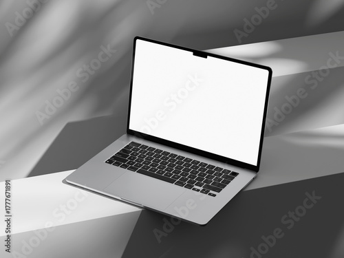 Laptop with a clean screen and shadows of greenery nearby