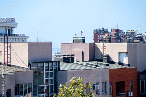 Wallpaper Mural Rooftop view of Belgrade, Serbia, featuring modern buildings with ladders, glass facades, and air conditioners, while the distant Ada Bridge and the dome of St. Sava Temple . Torontodigital.ca