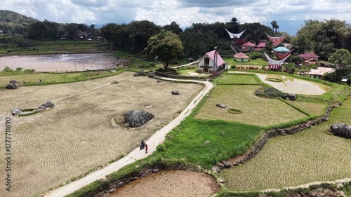 Aerial view of rice terraces near Rantepao, Tana Toraja, Indonesia, with lush greenery, water-filled paddies, and scattered rocks.	