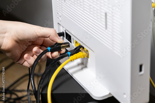 Foto Human hand plugging a black Ethernet cable into a white internet router, establi