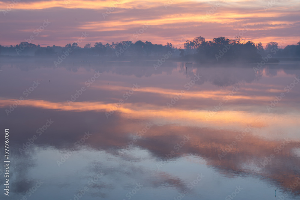 Fototapeta premium Jesienny wschó słońca we mgle, nad wodą.